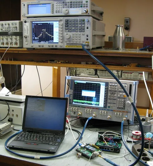 A professional RF electronics lab bench scene with an oscilloscope, signal generator, and DUT connected via coaxial cables, highlighting an SMA female to BNC male adapter in the signal chain. A professional RF electronics lab bench scene with an oscilloscope, signal generator, and DUT connected via coaxial cables, highlighting an SMA female to BNC male adapter in the signal chain.
