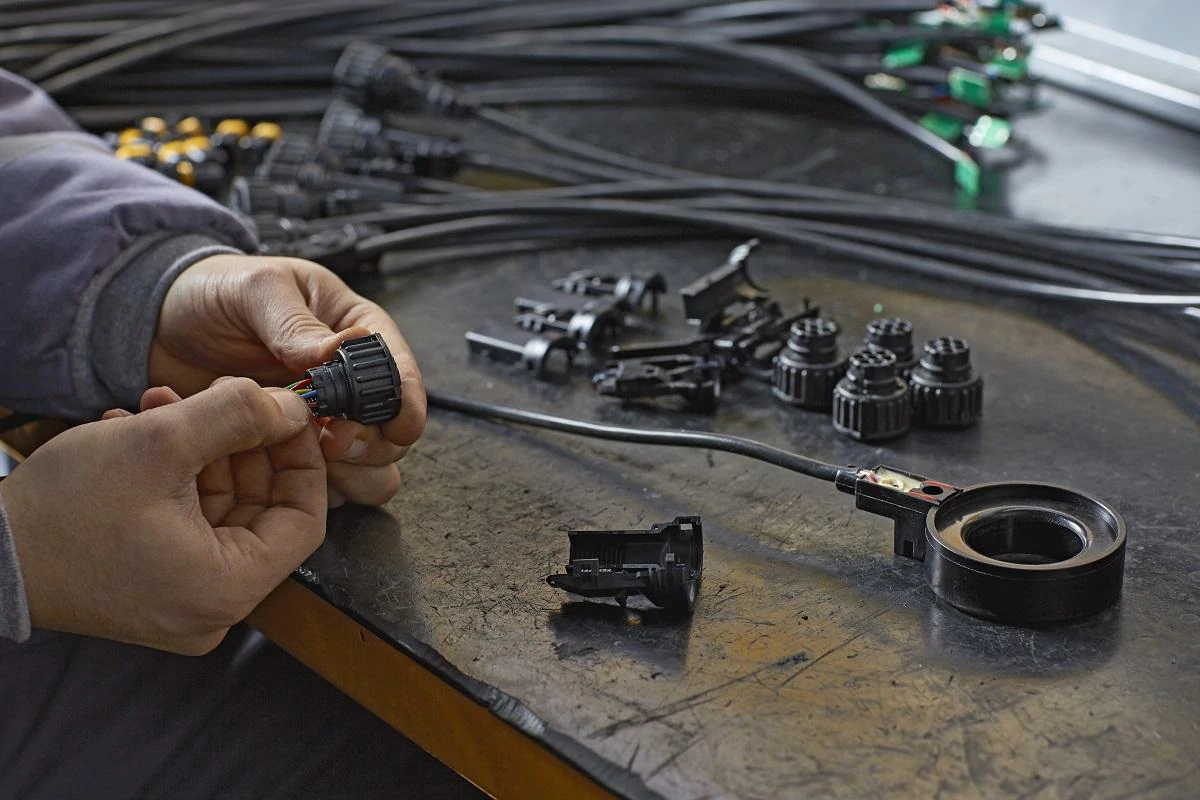 Worker assembling circular aviation connectors and industrial cable harnesses in production Worker assembling circular aviation connectors and industrial cable harnesses in production