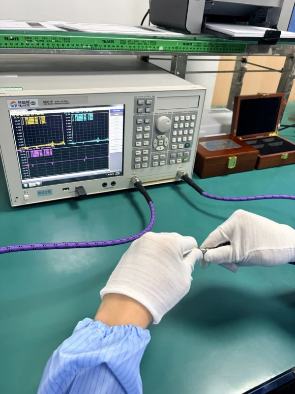 Technician testing an RF coaxial adapter with a vector network analyzer during quality inspection Technician testing an RF coaxial adapter with a vector network analyzer during quality inspection